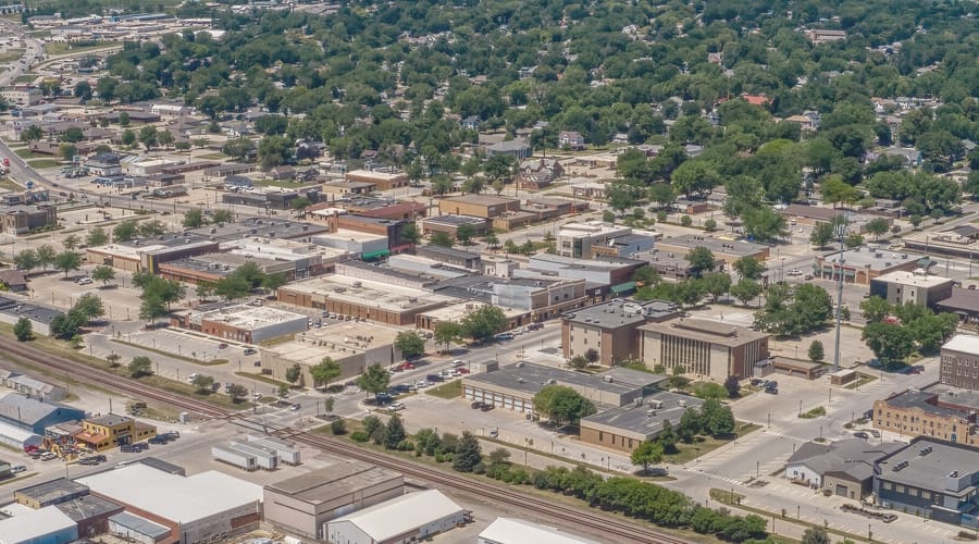 Downtown Carroll from the air, with the rail line, the tree canopy, and farmland and wind turbines beyond.