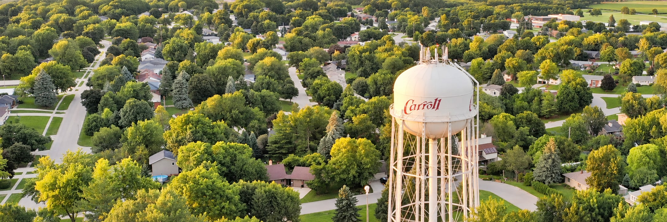 Carroll's white water tower above leafy residential streets in warm evening light.